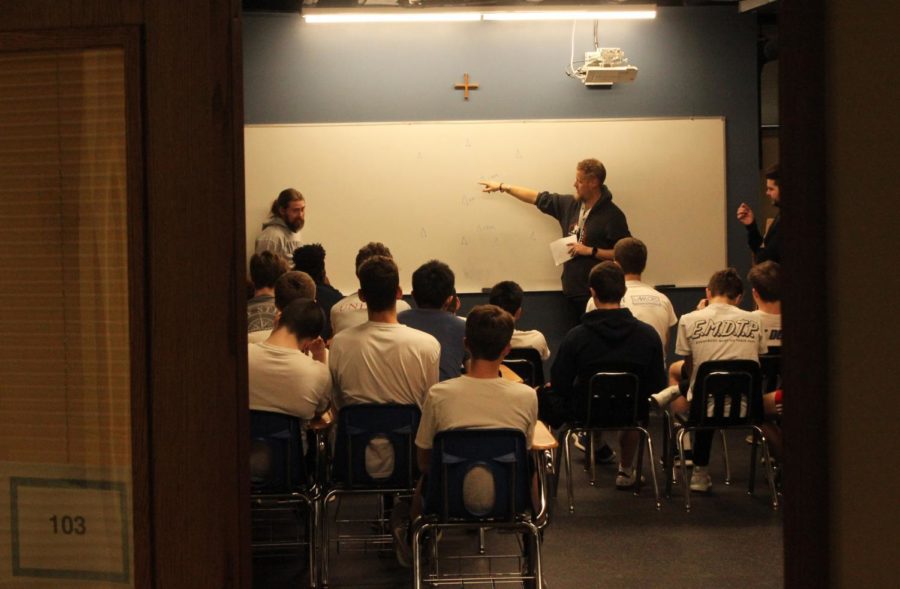 Reviewing strategy, head soccer coach Kevin Gray points out a particular play to the varsity team. The team meets in room 103 of the Benedict Building to go over formations, set pieces, and film.