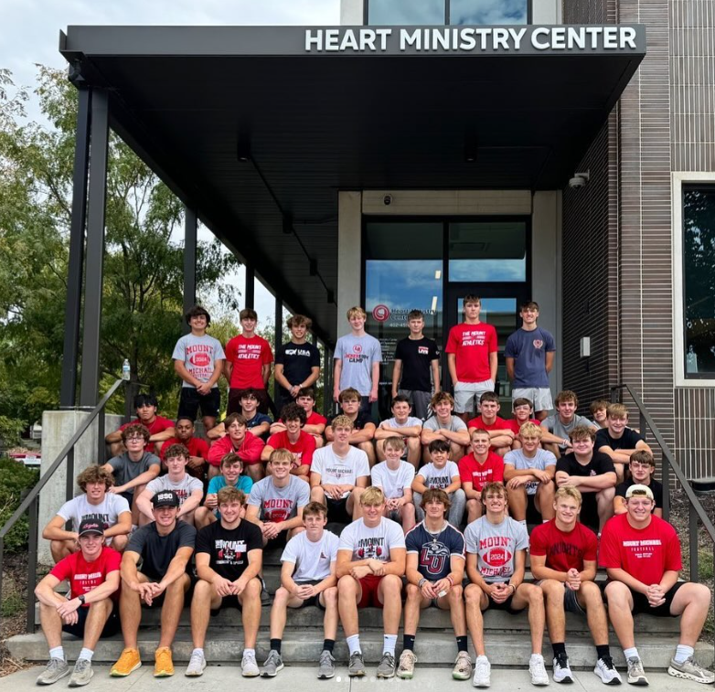 More than Muscle The football team poses for a picture in front of the Heart Ministry Center. Coaches and players spent the afternoon filling cars with food donations.